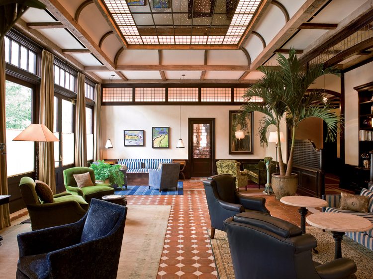 lobby com tetos de vigas de madeiras e sofas de veludo azul e verde